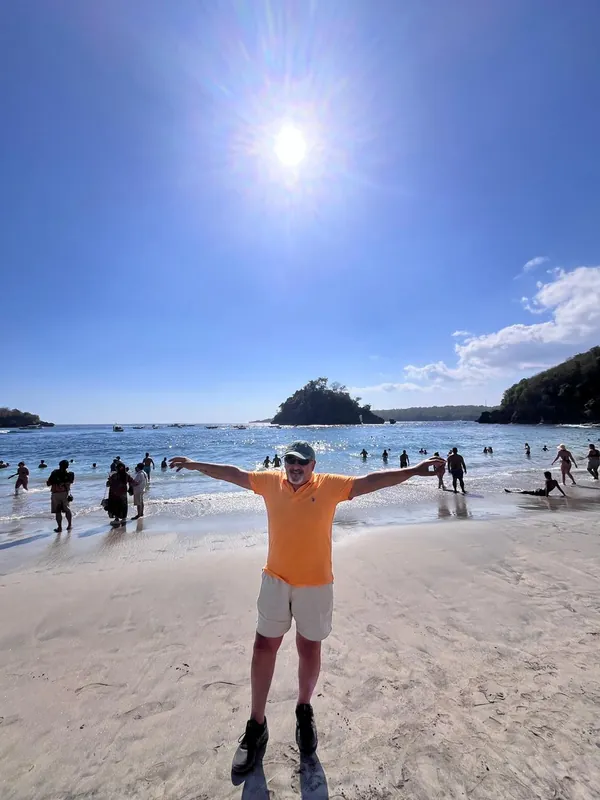 Guest with arms wide open on Crystal Bay beach under the sun